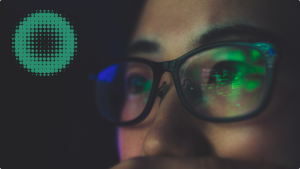 Luzes da tela de um computador refletidas nos óculos de uma pessoa