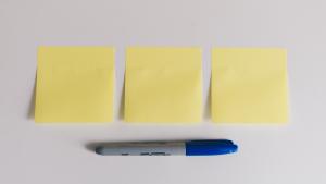 three empty yellow Post-it sticky notes in a row, with a blue-tipped Sharpie underneath