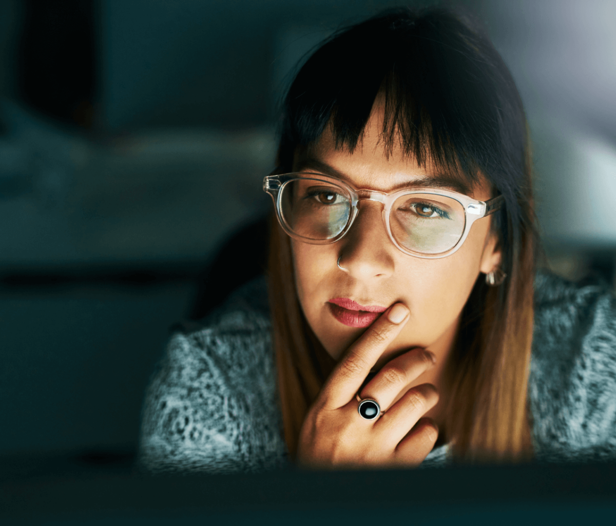 woman with glasses looking thoughtfully at a computer screen