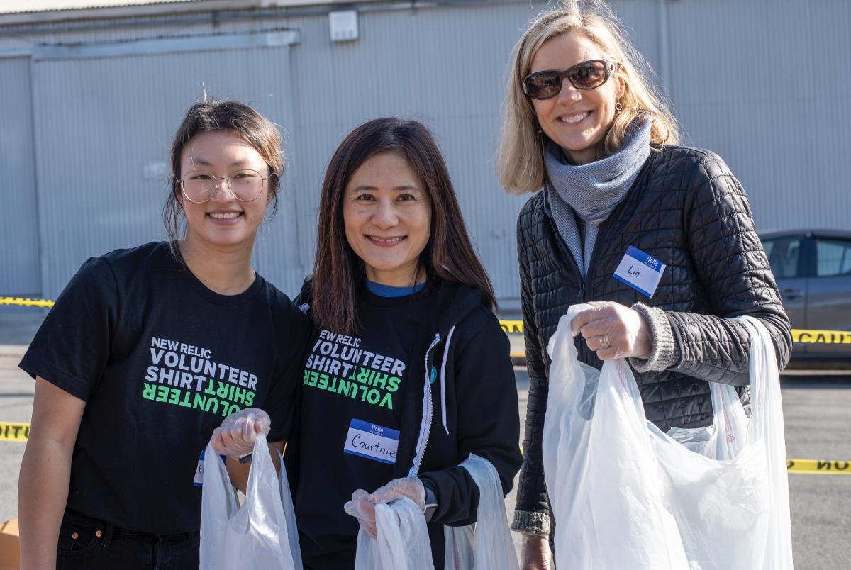 3 New Relic employees carrying grocery bags outside the San Francisco-Marin Food Bank, smiling and wearing New Relic Volunteer T-shirts.