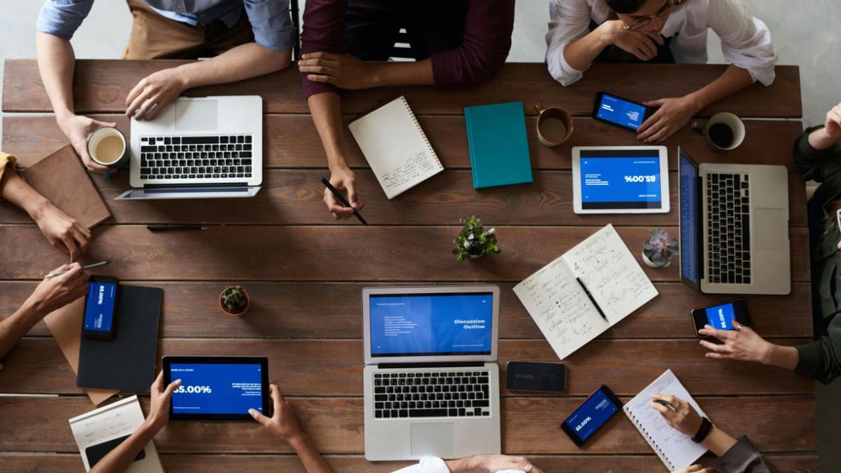 Webinar - multiple people working on laptops arranged around a desk