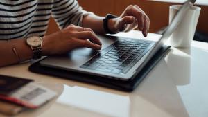 Hands typing on laptop