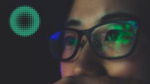 A person with glasses and reflection of a computer screen, round green graphic