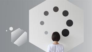 Sequência de pontos pretos em tamanho crescente formando um círculo em uma parede e uma pessoa com cabelo preto olhando para a parede