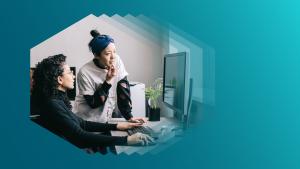 Photo of two people looking at a computer screen, one standing, one seated at a keyboard, viewed inside a hexagon.