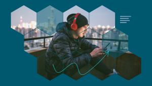 Sideview photo of a person with headphones holding and looking at a mobile phone, with a cityscape background