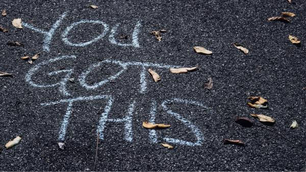 Chalk message on pavement YOU GOT THIS with a handful of stray leaves scattered all around