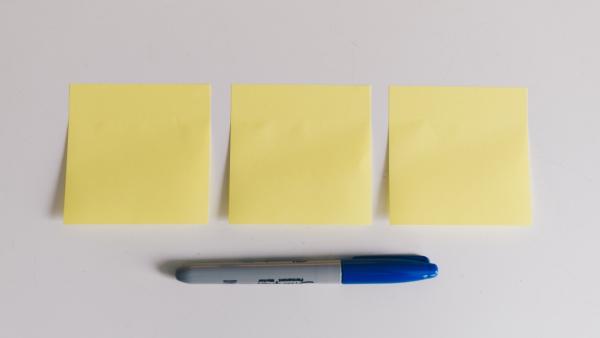 three empty yellow Post-it sticky notes in a row, with a blue-tipped Sharpie underneath