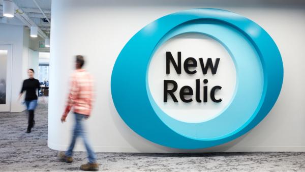 At the New Relic office, a large logo displayed on the wall and people walking around the corridor