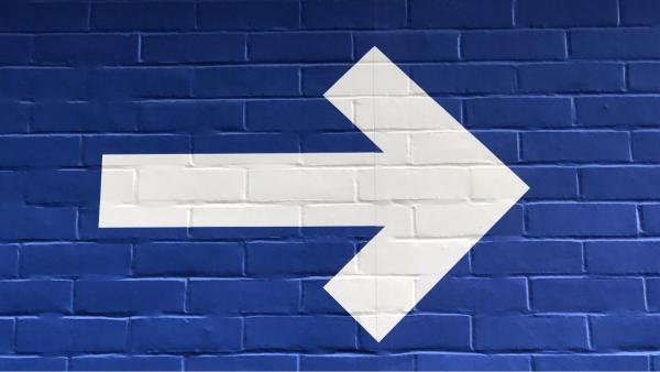 a brick tiled background in royal blue, with a large white arrow overlaid pointing to the right
