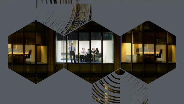 Mit drei Sechsecken überlagertes Foto dreier Fenster in einem Bürogebäude