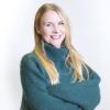 Delia Behrがカメラの前で腕組みをしてほほえんでいる従業員プロフィール写真。