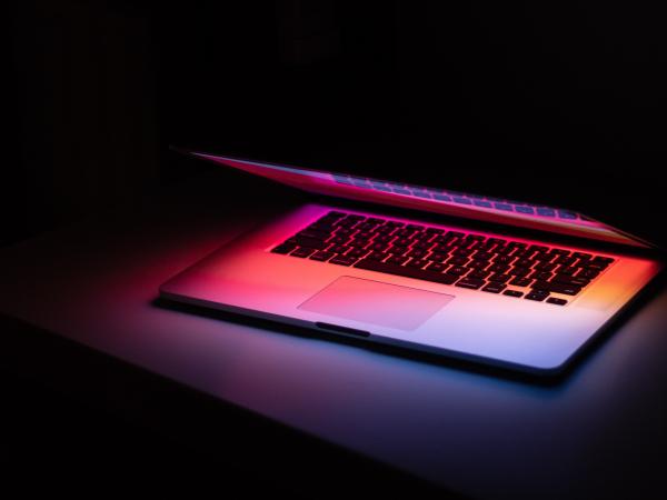 Devices - A laptop halfway open, on a darkened table, with a faint pink glow om-kamath-eL_FERodaT4-unsplash.jpg