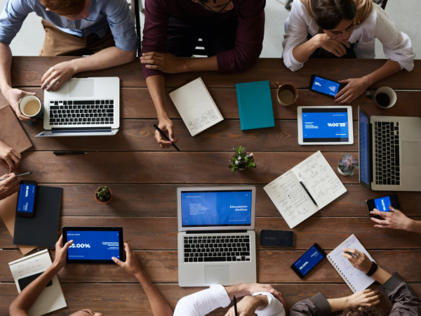 Webinar - multiple people working on laptops arranged around a desk