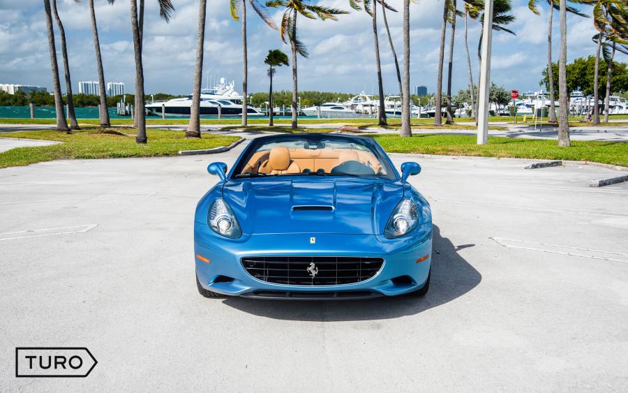 A blue convertible Ferrari sports car parked in an outdoor